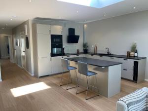 a kitchen with white cabinets and a island with bar stools at Luxury Modern Home near Gothenburg & 3 min t Beach in Billdal