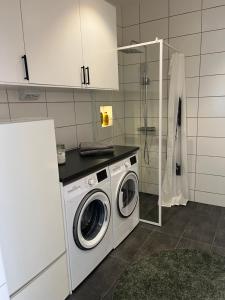 a kitchen with a washing machine and a shower at Luxury Modern Home near Gothenburg & 3 min t Beach in Billdal