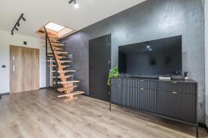 a living room with a television and a staircase at Apartament w Dolinie Sanu in Lesko