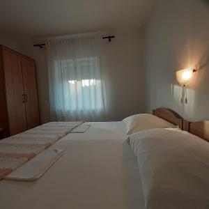 a white bedroom with two beds and a window at Piadora in Banjol