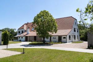 a white house with a tree in front of it at De Gulle Beemden in Hulshout