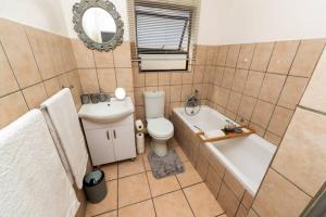 a bathroom with a toilet and a tub and a sink at Havens corner in Sandton