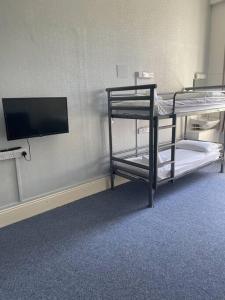 a room with two bunk beds and a flat screen tv at Marle Hall - Dorm Rooms (Blue) in Llandudno Junction