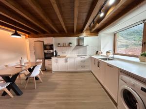 cocina con armarios blancos, mesa y ventana en Casa Maribel. Casa rural en Lebeña, Picos de Europa, en Lebena