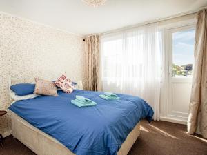 um quarto com uma cama com lençóis azuis e uma janela em Hookhills Holiday Home em Goodrington