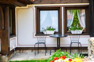 un patio con 2 sillas, una mesa y 2 ventanas en Къща ЕТНО en Koprivshtitsa