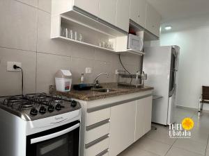 a kitchen with a stove and a sink and a refrigerator at Thel Ubatuba - Apto 27/A, Monte Carlo - Praia Grande in Ubatuba