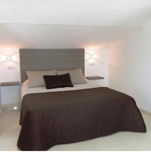 a bedroom with a large bed with a brown blanket at Albergue-Pensión Cabo da Vila in Finisterre