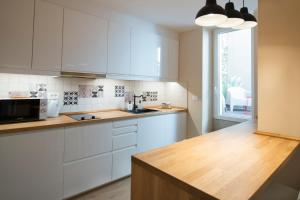 a kitchen with white cabinets and a sink and a window at Apartments E & E Piran in Piran