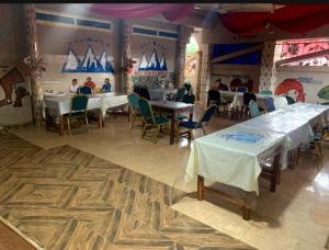 a restaurant with tables and chairs and people sitting at tables at Hôtel cœur des montagnes in Abomey