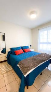 a blue bed with red pillows in a bedroom at Paseo de la Arboleda apartamento in Quetzaltenango