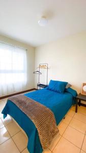 a bedroom with a blue bed with a blanket on it at Paseo de la Arboleda apartamento in Quetzaltenango