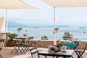 een patio met tafels en stoelen en uitzicht op de oceaan bij La dimora di Caboto B&B in Gaeta