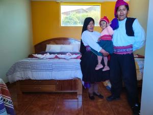 Taquile Inti Raymi Lodge في Huillanopampa: مجموعة اشخاص واقفين بجانب سرير