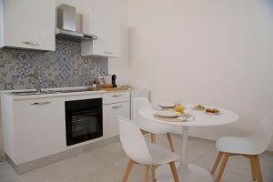 a white kitchen with a white table and chairs at Casa Sole in Lecce