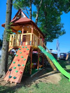 a play house with a slide in front of a tree at Apartament przy Wyciągu z jacuzzi in Bukowina Tatrzańska