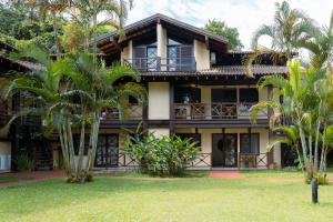 a house with palm trees in front of it at Flats de 1 e 2 dorm a 50m da Praia Maresias - Cond Lazer Completo in Maresias