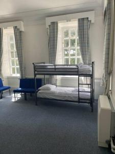 a bedroom with two bunk beds and two chairs at Marle Hall - Dorm Rooms (Yellow) in Llandudno Junction