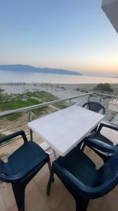 een witte tafel en stoelen op een balkon met uitzicht op het strand bij Relax Rental in Vlorë