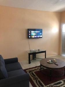 ein Wohnzimmer mit einem Sofa, einem Tisch und einem TV in der Unterkunft Paradise Haven in Nassau