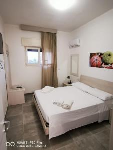 een slaapkamer met een groot wit bed en een raam bij Residence IL CARRUBO in Gallipoli