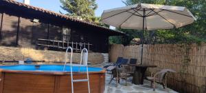 patio con ombrellone e piscina di Балтовата къща a Medven