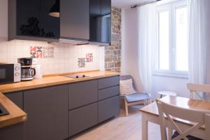 a kitchen with black cabinets and a table and a window at Apartments E & E Piran in Piran