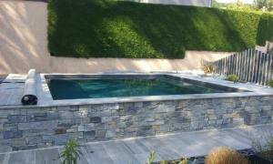 a swimming pool in a stone retaining wall with a fence at chambre dans maison avec piscine et cuisine in Saint-Étienne