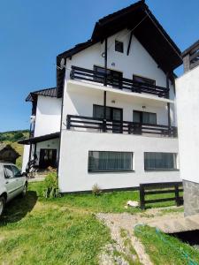 a white house with a car parked in front of it at Pensiunea Luca in Şirnea