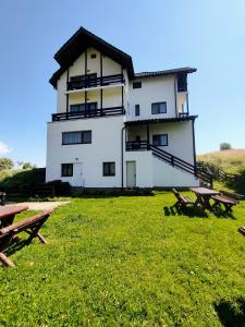 a building with two picnic tables in front of it at Pensiunea Luca in Şirnea