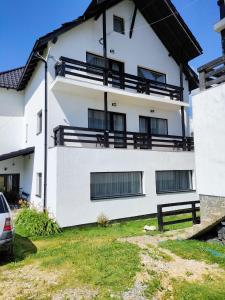 a white building with black balconies on it at Pensiunea Luca in Şirnea