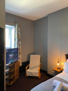 a bedroom with a bed and a chair and a television at Bay view rooms at Mentone Hotel in Weston-super-Mare