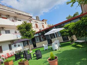 a yard with chairs and umbrellas in front of a building at Hotel Souvenir in Ercolano