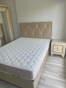 a bed in a bedroom with a nightstand next to a bed sidx sidx sidx at Mersin condominium Life City with pool and sea in Erdemli