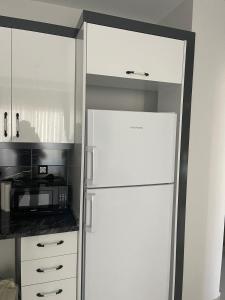 eine Küche mit einem weißen Kühlschrank und einer Mikrowelle in der Unterkunft Mersin condominium Life City with pool and sea in Erdemli