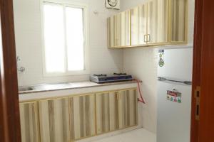 サラーラにあるRED-7 - Alwadi Salalahの木製のキャビネットと白い冷蔵庫を備えたキッチン