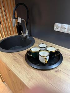 - un plateau avec quatre tasses à café sur un comptoir à côté d'un évier dans l'établissement Apartman Ena Fojnica, à Fojnica