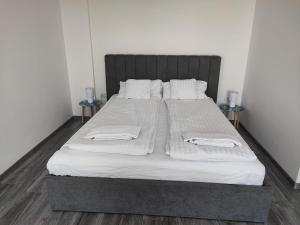 1 cama grande con sábanas blancas y almohadas. en Paradis Baile Felix, en Băile Felix