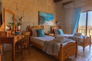 a bedroom with two beds and a table and a desk at Orchidea Xaghra in Il-Pergla