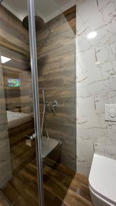 La salle de bains est pourvue d'une douche en verre et de toilettes. dans l'établissement Vila 90 Boutique Hotel, à Tirana
