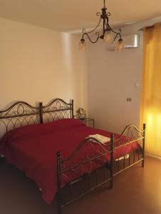 1 dormitorio con 1 cama con manta roja y lámpara de araña en Hotel Mondial 2, en Villasor