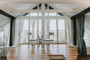 een woonkamer met een tafel, stoelen en ramen bij Villa Mimi in Sopron