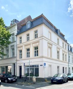 a white building with cars parked in front of it at Zehuus mit Domblick und Dachterrasse in Cologne