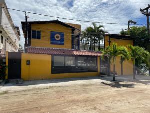 a yellow building with palm trees in front of it at Pousada Girassol in Porto De Galinhas