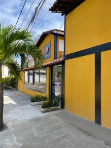 a yellow building with palm trees in front of it at Pousada Girassol in Porto De Galinhas
