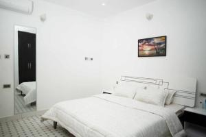 a white bedroom with a bed and a mirror at DMK Apartments in Abuja