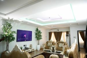 a living room with couches and a tv on the wall at DMK Apartments in Abuja