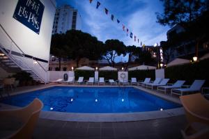 a swimming pool with lounge chairs and a building at Hotel Els Pins in Platja d'Aro