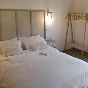 a large white bed with white sheets and pillows at Le Dune rooms in Cinigiano