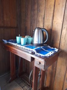 a tea kettle on a table with cups on it at Sítio pousada e Refúgio lazer e eventos in Santana do Livramento